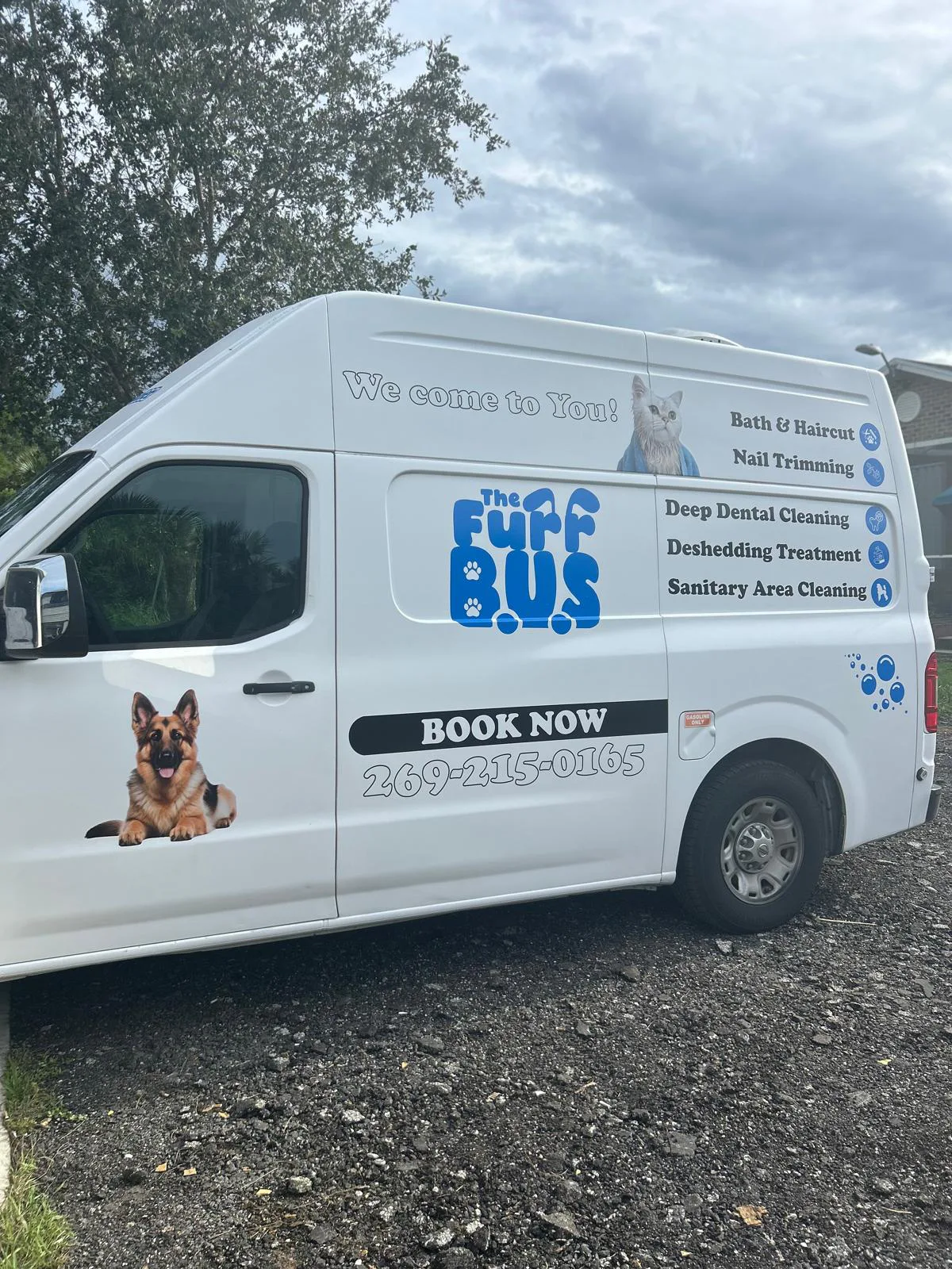 White mobile pet-service van with blue commercial graphics.