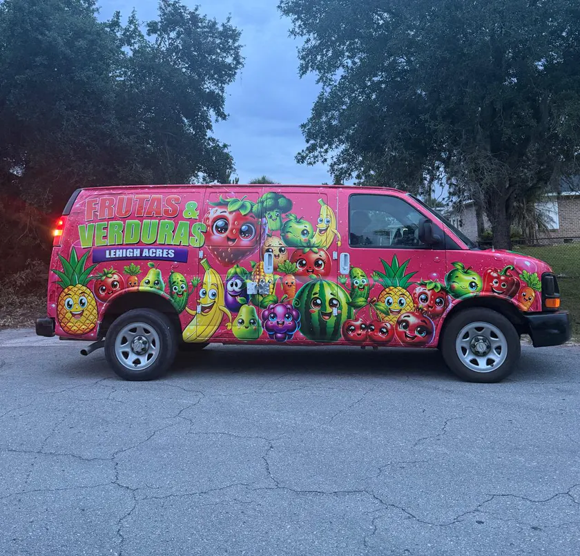 Bright pink commercial van covered with colorful fruit and vegetable graphics.