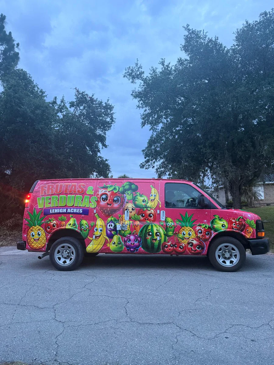 Bright pink commercial van wrapped with colorful fruit graphics.