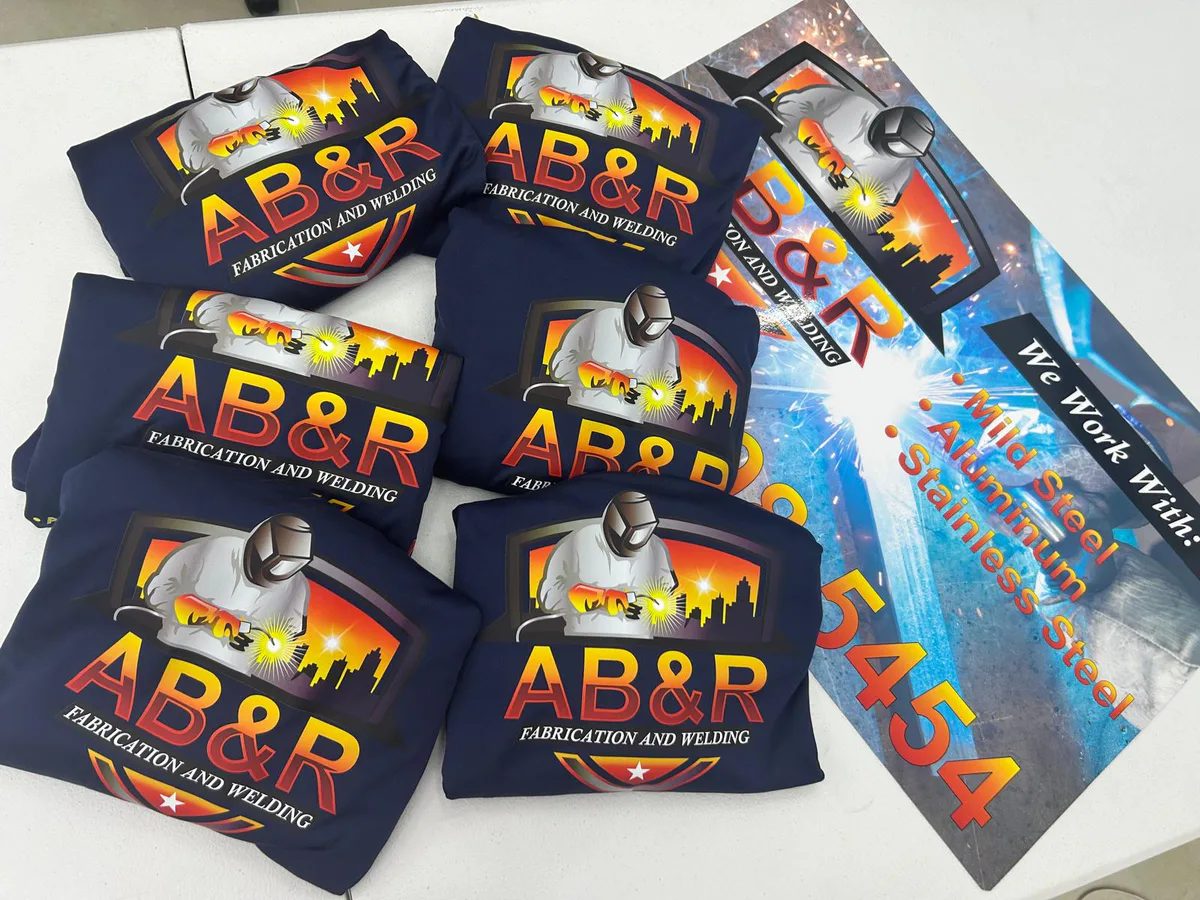 Branded welding shirts displayed with a matching printed banner.